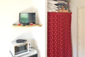 a room with a microwave and a red curtain at Studio avec vue panoramique sur la montagne - Le Dévoluy, 18 m² in Le Dévoluy