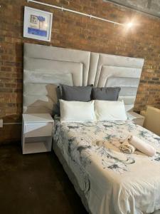 a bedroom with a large white bed and a brick wall at The Hills by maboneng in Johannesburg