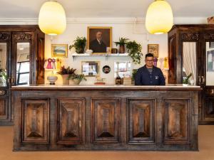un homme debout derrière un bar en bois dans une pièce dans l'établissement Palihotel Melrose, à Los Angeles