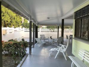 a porch with white chairs and tables on a building at Villa de standing avec piscine à Saint-François in Saint-François