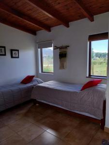 two beds in a room with two windows at Entre Montañas in Tafí del Valle