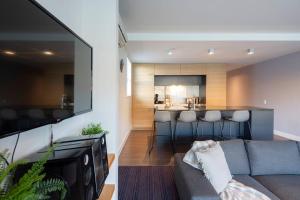 a living room with a gray couch and a kitchen at Mantra 2-- Lakeside Walking Track- Free Parking in Queenstown