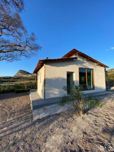 a small white house in the middle of a field at Chalé Frutas Especiais in Mucugê