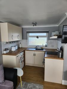 a small kitchen with white cabinets and a window at Charming 2-Bed Chalet in Selsey