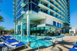 a hotel swimming pool with blue chairs and a building at Stunning Escape Top Floor Strip-View Studio 31316 in Las Vegas