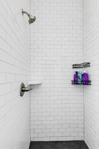 a white tiled bathroom with a shower with two shelves at Quaint Escape for 2 Near Richmond Battlefield Park in Richmond