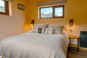 een slaapkamer met een wit bed en 2 ramen bij Berberis Apart in El Chalten