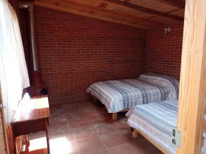 a bedroom with two beds and a brick wall at Hotel DE LAS MARIPOSAS in Valle de Bravo
