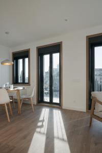 a living room with a table and chairs and windows at Avós Apartamentos in Monforte de Lemos +26 photos