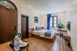 a bedroom with a bed and a desk in a room at Alba Sand Hotel & Spa Phú Quốc in Phu Quoc