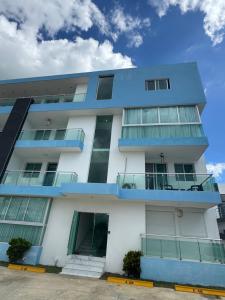 a white apartment building with blue balconies at Alojamiento en Boca Chica in Boca Chica