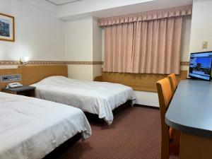 a hotel room with two beds and a desk at Hotel Alpha-One Hofu in Hofu