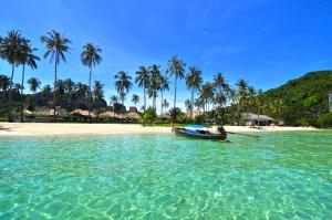 una barca in acqua su una spiaggia con palme di Phi Phi Little Star Resort a Phi Phi Don