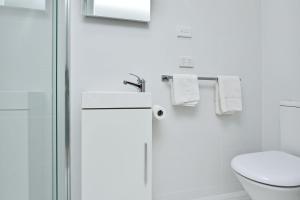 a white bathroom with a toilet and a shower at Gidget's Getaway in Nelson Bay +14 photos