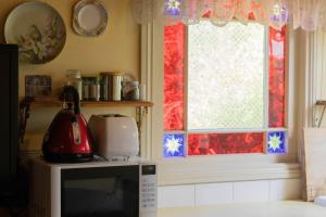 a kitchen with a microwave and a window at Rose Petal Cottage Quaint Studio In Ballarat in Ballarat +5 photos