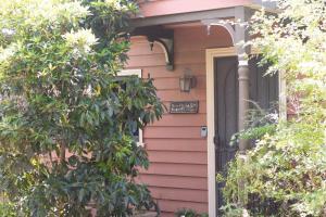 a pink house with a clock on the door at Rose Petal Cottage Quaint Studio In Ballarat in Ballarat