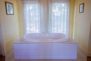 a bath tub in a bathroom with a window at Rose Petal Cottage Quaint Studio In Ballarat in Ballarat