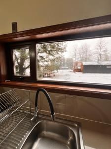 a kitchen sink and a window with a snow covered yard at Cabañas Altos del Sollipulli in Rumiñano +34 photos