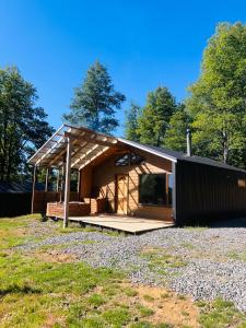 een klein huis met een houten dak op een veld bij Cabañas Altos del Sollipulli in Rumiñano