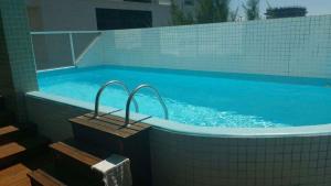 a large swimming pool with blue water and tiles at Apt 3 Dorm Super equipado Vista deslumbrante mar in Capão da Canoa