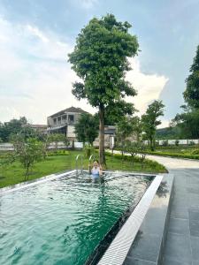 eine Frau in einem Swimmingpool mit einem Baum in der Unterkunft Rose Villa Thai Nguyen - Venuestay in Thượng Nhân