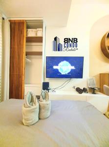 a bedroom with a bed with a tv and shoes at Studio2 - BNB Condo Rentals CDO in Lapasan