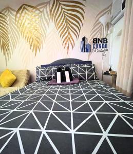 a bedroom with a black and white bed with palm leaves on the wall at Studio2 - BNB Condo Rentals CDO in Lapasan