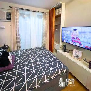a bedroom with a bed and a flat screen tv at Studio2 - BNB Condo Rentals CDO in Lapasan