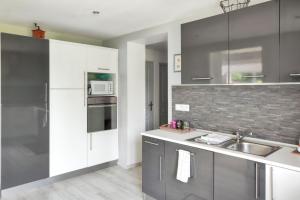 a kitchen with white cabinets and a sink at Charmante Maison à Fort-Moville avec Terrasse Privée in Fort-Moville