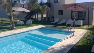 a pool with an umbrella next to a house at Maderos Apart in Federación
