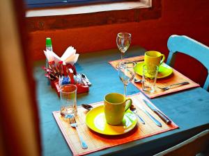 a blue table with yellow plates and glasses on it at CkuriQuechuaexperience in San Pedro de Atacama