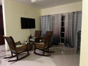 a living room with chairs and a tv on the wall at Casa de alquiler FIGARO in Villa Clara