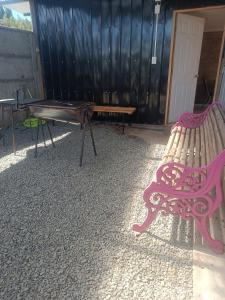 a pink bench and a table in a yard at Cabaña Renacer a 10 min del aeropuerto in Puerto Montt