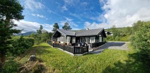 een huis met een zwart dak op een groen veld bij Panorama Cabin - Stunning Mountain Views and Outdoor Jacuzzi Option in Bjorli