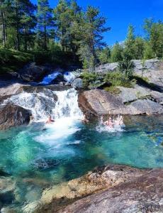 een groep mensen die in een rivier zwemmen bij Panorama Cabin - Stunning Mountain Views and Outdoor Jacuzzi Option in Bjorli