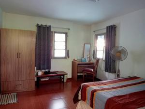 a bedroom with a bed and a desk and windows at Young and Beautiful in Bangkok