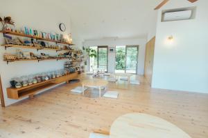 een woonkamer met een tafel en stoelen en planken bij 1日2組限定オーシャンビューのお宿-MANANI House- in Ōura +20 foto's