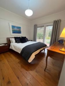 Un dormitorio con una cama y suelo de madera. en Treetops at Harrietville, en Harrietville