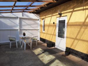 a patio with a table and chairs and a white door at Hyggeligt hus på landet in Ansager