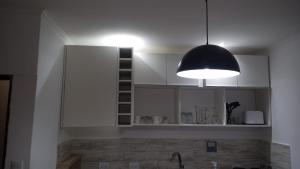 a kitchen with white cabinets and a black light fixture at Atenea B in Chivilcoy