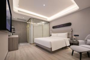 Un dormitorio con una cama blanca y un televisor. en Atour X Hotel Wuhan Wuhan Yellow Crane Tower Yangtze River Bridge, en Han-yang-hsien 5 fotos más