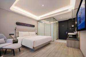 Un dormitorio con una cama blanca y un televisor de pantalla plana. en Atour X Hotel Wuhan Wuhan Yellow Crane Tower Yangtze River Bridge, en Han-yang-hsien