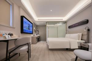 Un dormitorio con una cama blanca, un escritorio y un televisor. en Atour X Hotel Wuhan Wuhan Yellow Crane Tower Yangtze River Bridge, en Han-yang-hsien