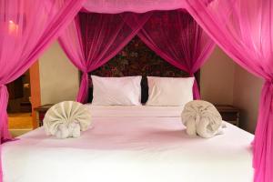a pink canopy bed with two white towels on it at Bali Bohemia Huts in Ubud
