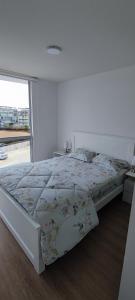 a bed in a white room with a large window at Apartamento San Bartolo in San Bartolo