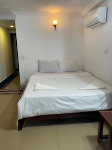 The ream beach hostel في Phsar Ream: غرفة نوم بسرير ذو شراشف بيضاء واضاءة