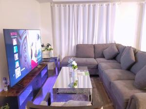 a living room with a couch and a flat screen tv at New 3-BR Home Near Falls with King Bed 75 Inch TV and Parking in Thorold