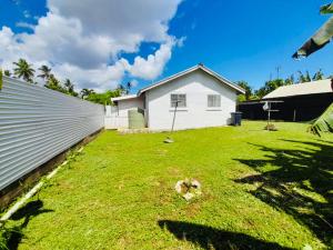 a backyard with a white house and a grass yard at Private Twin Room - Tonga Coral Cottage in Hofoa