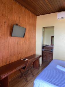 a bedroom with a desk and a bed and a television at Bima Sakti Homestay Echo Beach Canggu in Canggu