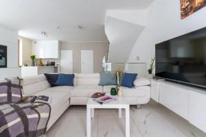 a white living room with a white couch and a table at Exclusive townhouse Maciejki with garden and terrace near Warsaw in Nowa Wola